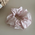 Detailed close-up of a pink fabric scrunchie with soft cotton texture and woven label - Pink