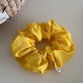Detailed macro view of bright yellow fabric scrunchie with soft cotton texture and woven label - Yellow