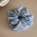Detail eines hellblauen großen Chiffon-Haargummis mit Strasssteinen und weichen Falten - Blau