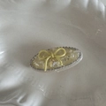 Detailansicht der ovalen, hellgelben Haarklammer mit Schleife und glitzernden Strasssteinen - Gelbes Oval