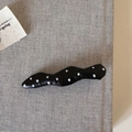 Detail einer wellenförmigen schwarzen Haarklammer mit weißen Punkten und Glanz - Schwarz Welle Polka Dot Leder