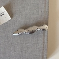 Nahaufnahme einer gehämmerten silbernen Haarspange mit schwarzen Punkten auf grauem Stoff - Silber Welle Polka Dot Leder