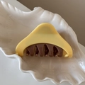 Gros plan d'une pince à cheveux bicolore posée sur un plateau en céramique coquillage - Triangle / Jaune