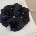 Macro detail of black pleated satin scrunchie decorated with elegant white pearls - Black