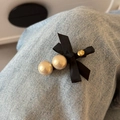 Dettaglio del fermaglio per capelli con fiocco in raso nero e doppie perle su jeans blu - Nero