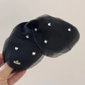 Dettaglio di un fermaglio a farfalla in tulle nero con cristalli e scritta Love - Nero