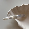 Dettaglio del fermaglio in acetato perlato iridescente con scritta Barrette La France - Bianco Trasparente