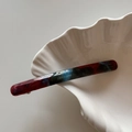 Close-up of marble acetate hair barrette with Barrette La France engraving on shell tray - Blue Red