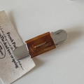 Macro shot of silver brushed metal hair clip with amber acetate slab and engraved logo - Brown