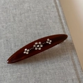 Detail van vintage acetaat haarklem met sprankelende strass bloemmotieven voor een retro look - koffiekleur