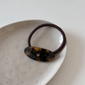 Macro de l'élastique à cheveux en acétate avec nœud et strass sur assiette céramique - Écaille de tortue