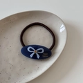 Detail von blauem Acetat-Haargummi mit Schleife und Strass auf einem Keramikteller - Blau