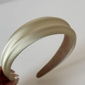 Dettaglio del cerchietto in raso pieghettato color oro champagne con imbottitura spessa - Verde