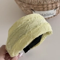Détail de serre-tête en dentelle jaune pâle avec motifs floraux et texture en maille - Jaune
