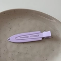 Detail view of a matte purple metal duckbill hair clip on a gray ceramic plate - Purple