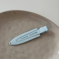 Detail of light blue matte metal hair clip on a beige ceramic plate - Blue