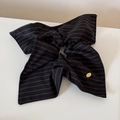 Detail eines großen schwarz gestreiften Stoff-Haargummis mit einer goldenen Metallplakette - Schwarz