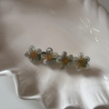 Dettaglio di quattro fermagli per capelli a fiori azzurri con centro dorato su piatto - Verde Trasparente