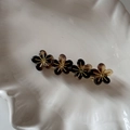 Détail d'une barrette à fleurs en résine ambrée avec pistils dorés sur une coupelle blanche - Écaille Claire