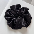 Close-up of black satin hair scrunchie with detailed 3D rose relief pattern texture - Rose Embossed-Black