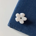 Close-up van een witte bloem haarklem met zwarte kraal op een achtergrond van denim stof - Wit