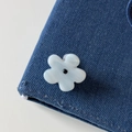 Detailed view of denim fabric texture featuring a blue and white flower embellishment - Blue