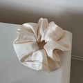 Detalle de un coletero grande de satén crema con textura brillante y pliegues suaves - Beige