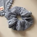 Gros plan du chouchou bleu clair avec nœuds brodés sur tissu en mousseline plissée - Bleu