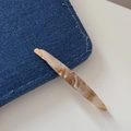 Macro shot of slender marble resin hair clip on denim fabric with handmade engraving - Apricot Marble