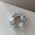 Détail d'un chouchou floral avec bord à volants en satin bleu clair et étiquette handmade - Frais à Volants Petit-Bleu