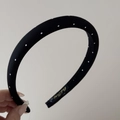 Detailed close-up of a black fabric headband with white polka dots and gold label - Narrow Headband / Black