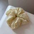 Detail view of large cream polka dot scrunchie with soft silk texture and micro brand tag - Scrunchie / Yellow
