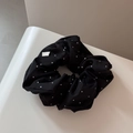 Close-up of black scrunchie with white polka dots featuring a small white side label - Scrunchie / Black