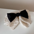 Detailed close-up of a vintage black silk bow hair clip with white floral lace trim - Black