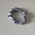 Détail d'un chouchou en satin gris argenté avec une perle décorative lavande - Bleu
