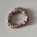 Detail eines Satin-Haargummis mit weichem Faltenstoff und stabiler Verbindungsschnalle - Champagner