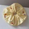 Detail van gele stoffen scrunchie met handgemaakte kleurrijke kralenbloemen en stiksels - Geel