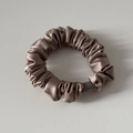 Detail eines champagnerfarbenen Satin-Scrunchies mit Seidentextur und Elastikband - Aprikose