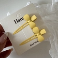 Détail de deux barrettes à cheveux nœud jaune mat en métal sur une carte de support - Jaune