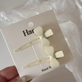 Set of two creamy white bow hair clips on card with matte finish and minimalist embossed design - White