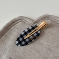Macro detail of oval checkerboard acetate hair clip with gold metal and handmade logo - Plaid