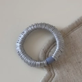 Détail d'un chouchou en satin gris argenté avec plis doux et attache en plastique bleue - Bleu