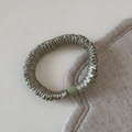 Gros plan détaillé du chouchou en satin avec boucle mate sur fond de tissu blanc élégant - Vert