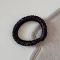 Close-up of seamless black silk scrunchie with pleated texture and round connector - Dark Coffee