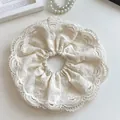 Detailed close-up of oversized bohemian lace scrunchie with hollow embroidery texture - Off White