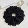 Detailed macro view of black lace scrunchie with hollow floral embroidery and textures - Black