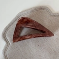 Dettaglio di una grande molletta a triangolo cava con texture marmorizzata marrone su lino - Stile Triangolo Marmo Marrone