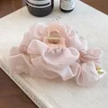 Dettaglio della molletta per capelli in garza rosa con cuore dorato su libro - Rosa