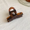 Dettaglio molletta per capelli ambra tartarugata con molla su sfondo minimalista - Caramello Opaco