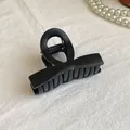 Dettaglio della molletta per capelli nera opaca con molla in metallo su lino bianco - Nero Opaco